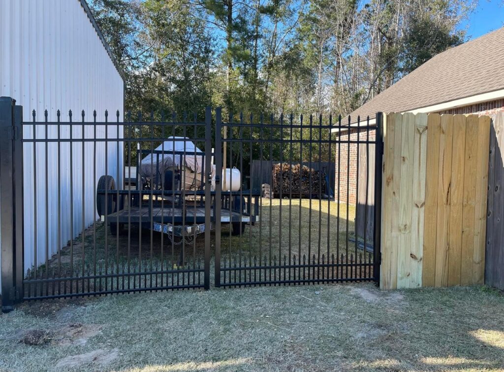 A combination black metal and wooden privacy fence with a gate, installed by JH Fencing in Lawrence, KS.