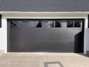 A sleek black modern garage door with rectangular windows, installed by Rainier Garage Door in Bellevue, WA.