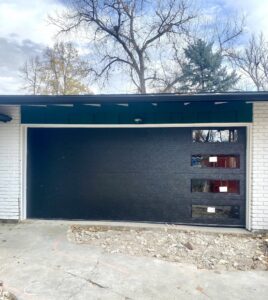 A sleek black modern garage door with vertical windows installed by Lion Heart Garage Doors in Thornton, CO.