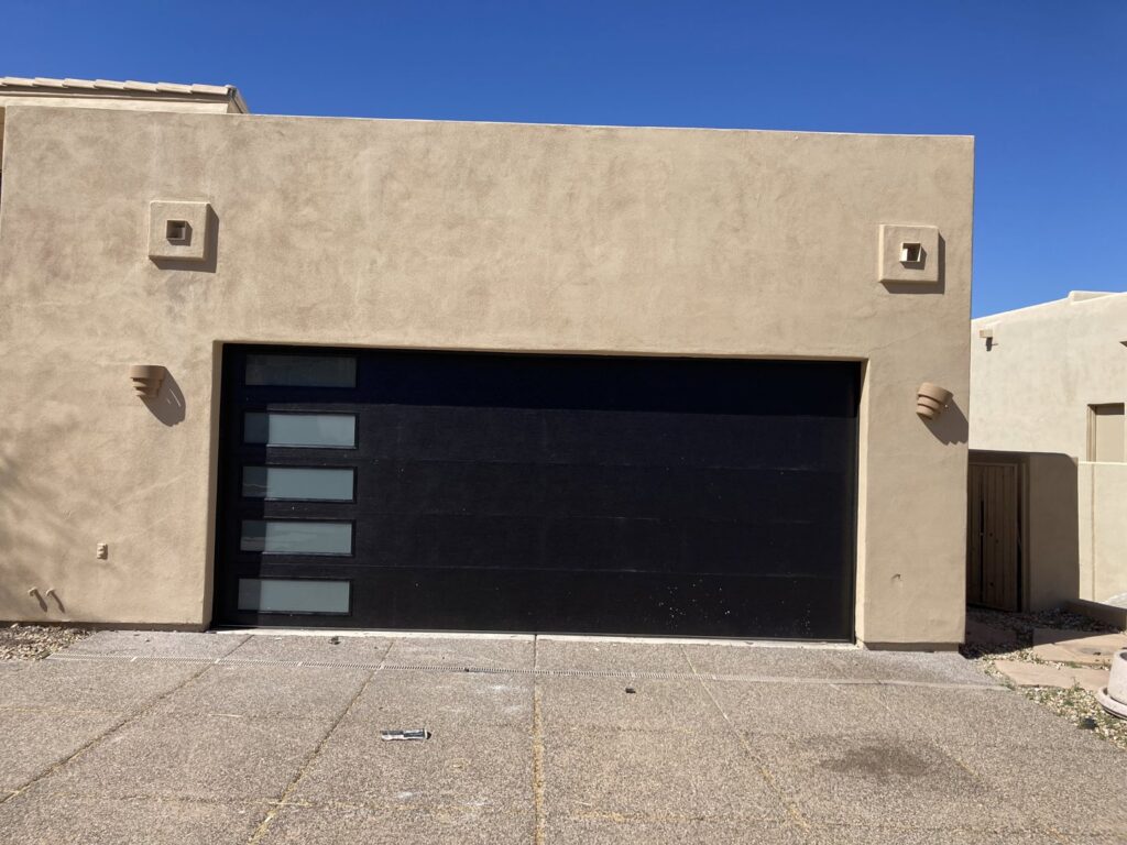 A newly installed black modern garage door with horizontal glass panels by Anew Garage by Jon's Garages in Surprise, AZ.