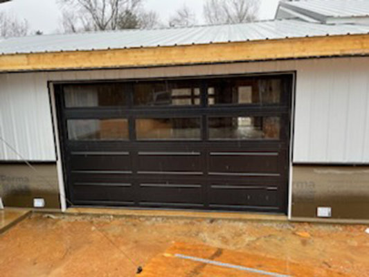 Installation of a sleek black modern glass garage door on a new construction project by Summers Garage Door in Denver, CO.