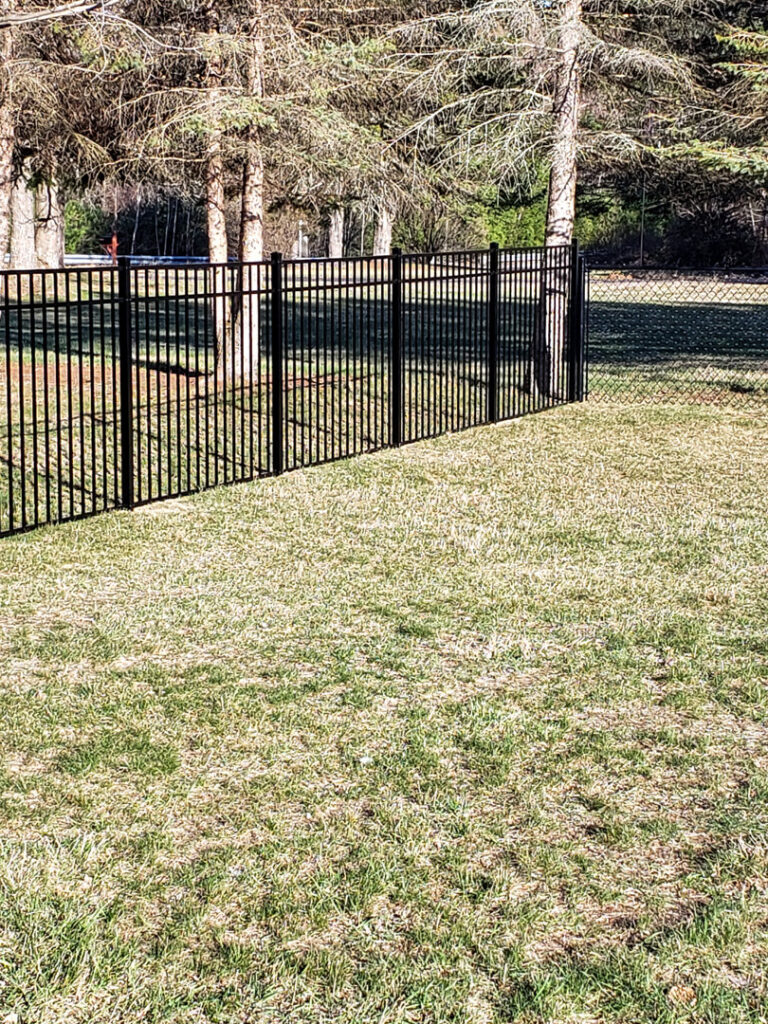 A stylish black ornamental aluminum fence installed in a grassy backyard by Sullivan & Sons Fence LLC in Hudson, NH.