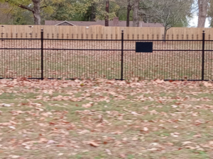 Black ornamental iron fence with a wood privacy fence in the background by Rice&Family Fencing LLC in Greenfield, TN.