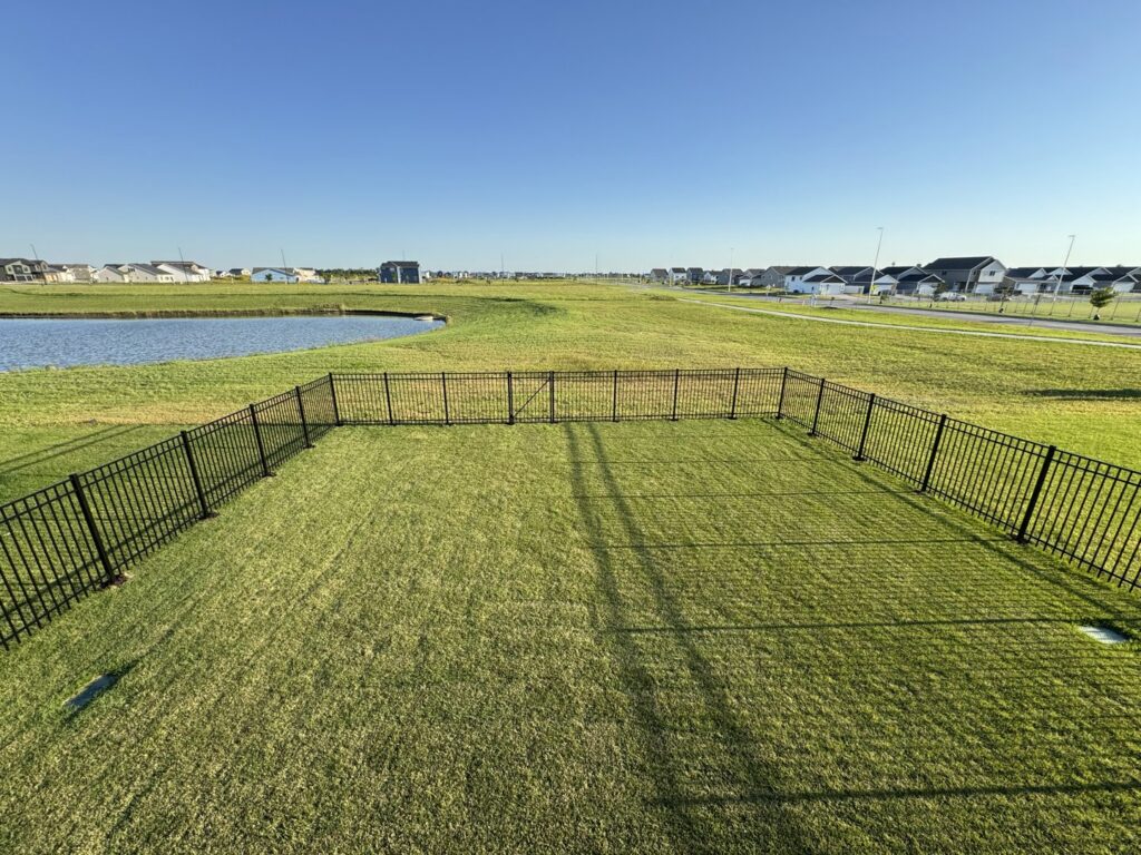 A black ornamental metal fence enclosing a dog run area by Aces Deck and Fence in Fargo, ND