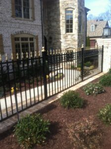 A black ornamental metal fence with decorative gold finials bordering a walkway by Georgia Select Fence in Senoia, GA.