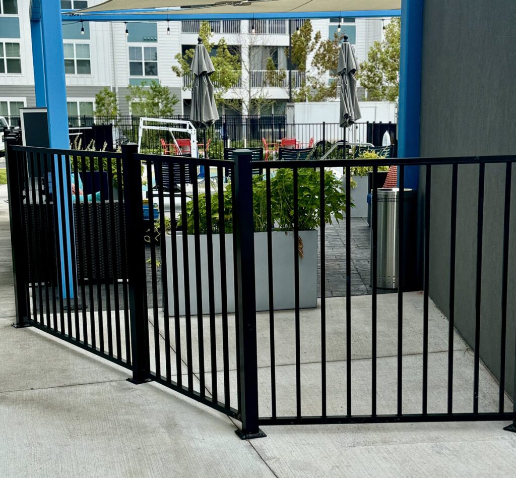 A black ornamental fence enclosing an outdoor patio seating area, installed by Superior Fence & Rail of North Shore in Gulfport, MS.