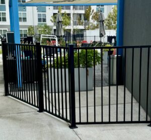 A black ornamental fence enclosing an outdoor patio seating area, installed by Superior Fence & Rail of North Shore in Gulfport, MS.