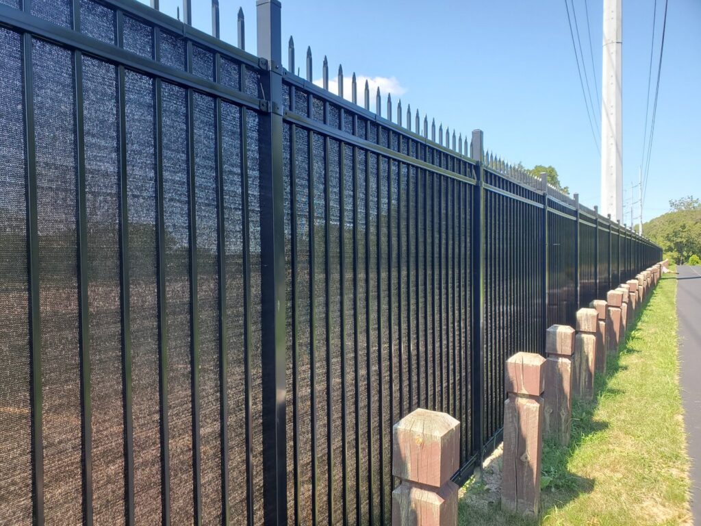 A tall black ornamental iron fence with privacy screening installed along a roadside by Top Notch Fence in East Bethel, MN