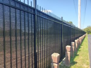 A tall black ornamental iron fence with privacy screening installed along a roadside by Top Notch Fence in East Bethel, MN
