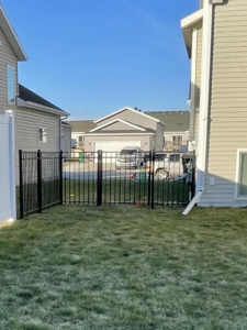 A newly installed black ornamental fence section with a gate, providing a secure boundary between two residential homes by VASE Construction, LLC in Fargo, ND.