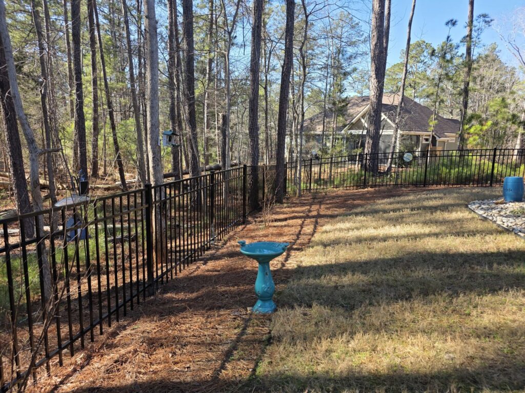 A black ornamental metal fence installed in a wooded residential backyard by East Georgia Fence in Evans, GA.