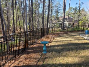 A black ornamental metal fence installed in a wooded residential backyard by East Georgia Fence in Evans, GA.
