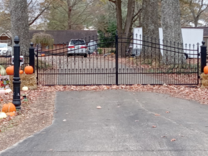 A large black ornamental iron driveway gate installed by Rice&Family Fencing LLC in Greenfield, TN.