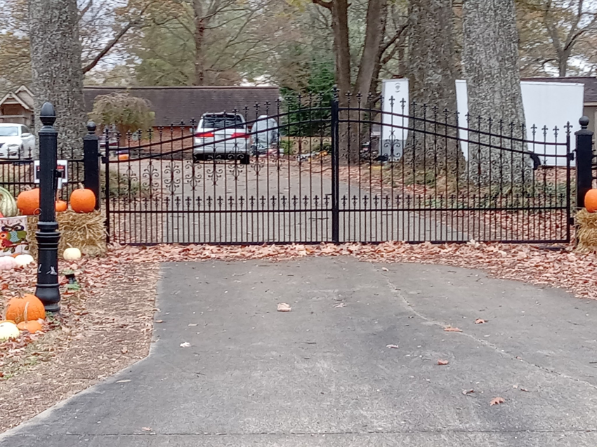 A large black ornamental iron driveway gate installed by Rice&Family Fencing LLC in Greenfield, TN.