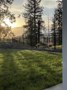 A black ornamental iron fence installed in a backyard at sunset by Crows Quality Fencing in Spokane Valley, WA.