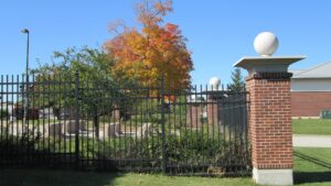 An elegant black ornamental iron fence with brick pillars and decorative finials by Statewide Fencing, Inc. in Racine, WI.