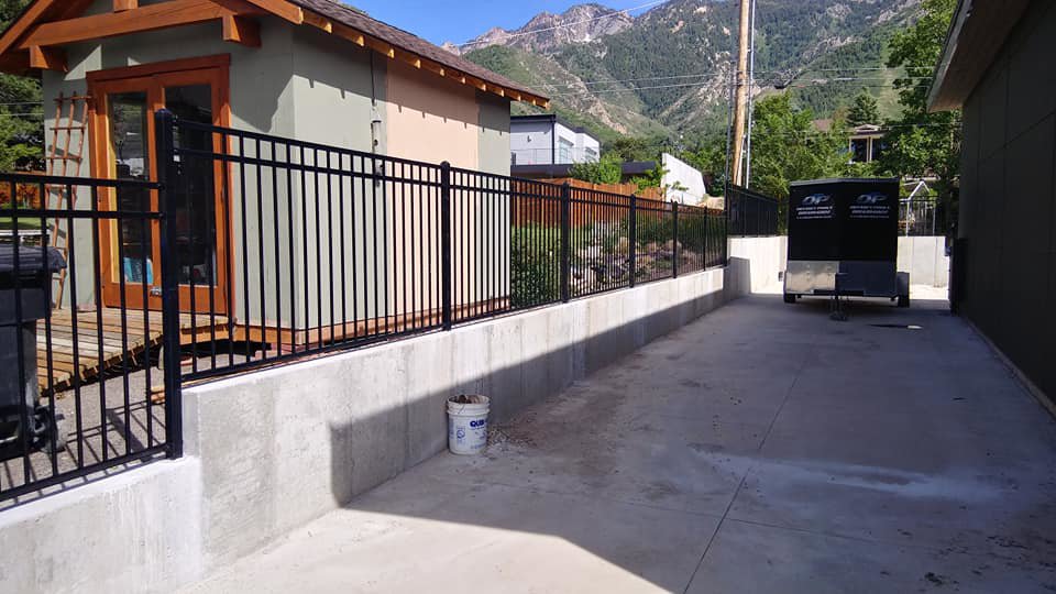 A black ornamental iron fence installed along a concrete retaining wall by Allied Fence Co in Tulsa, OK.