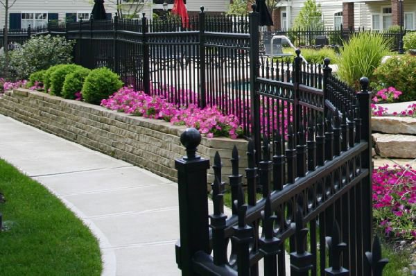 A black ornamental iron fence surrounding a beautifully landscaped area, installed by Ozark Fence in Lakewood, CO.