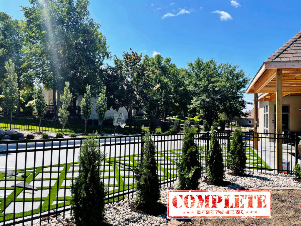 A black ornamental iron fence enclosing a beautifully landscaped yard by Complete Fence, LLC in West Chicago, IL