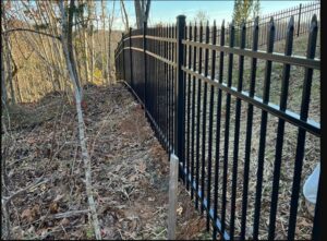 A black ornamental iron fence installed on a sloped terrain by Kelley Fence and Gate in Eva, AL.