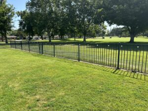 A durable black ornamental iron fence bordering a green park or golf course, installed by Mega Fence in Thornton, CA.