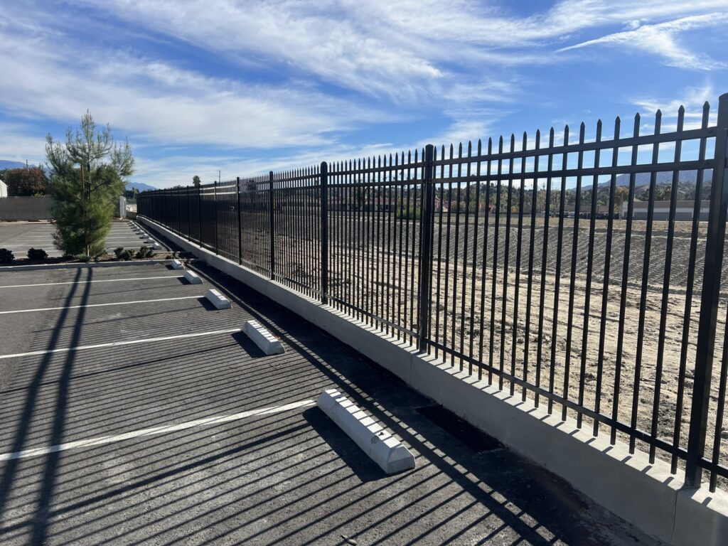 A black ornamental iron fence installed along a parking lot by No Limit Fence Company in Huntington Beach, CA.