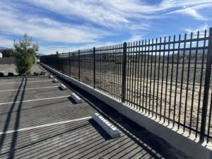 A black ornamental iron fence installed along a parking lot by No Limit Fence Company in Huntington Beach, CA.