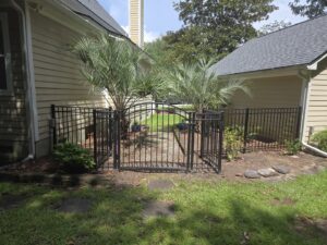 A black ornamental iron gate installed on a pathway between two homes by JB FENCE Brothers company llc in North Charleston, SC.