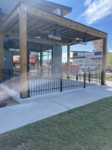 A black ornamental iron fence enclosing an outdoor patio area for a commercial business by Crompton Fence Company in Charleston, SC.