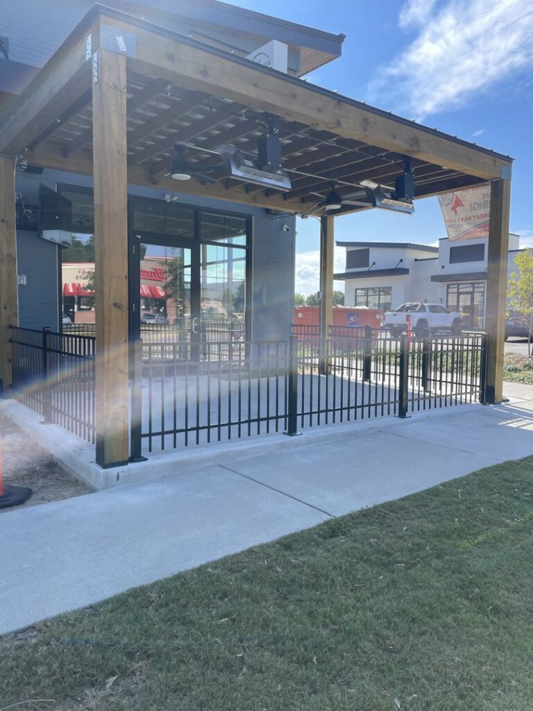 A black ornamental iron fence enclosing an outdoor patio area for a commercial business by Crompton Fence Company in Charleston, SC.