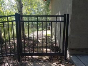 A black ornamental iron walkway gate providing access to a backyard path by Allied Fence Co in Tulsa, OK.