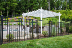 A black ornamental metal fence surrounding a backyard patio with a white pergola, installed by Western Fence & Landscape Supply in Caldwell, ID.