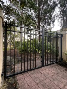 A black ornamental metal double gate with stone pillars, installed by Golden Eagle Fencing in Tampa, FL