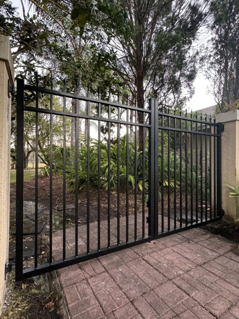 A black ornamental metal double gate with stone pillars, installed by Golden Eagle Fencing in Tampa, FL