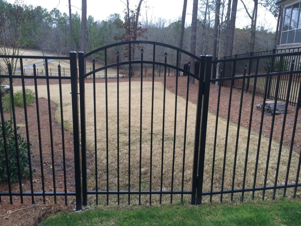 A black ornamental metal fence with an elegant arched gate installed by East Georgia Fence in Evans, GA.