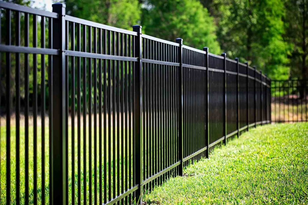 A sleek black ornamental metal fence installed in a spacious green area by Discount Fence Supply in Great Falls, SC.