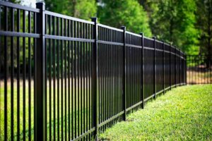 A sleek black ornamental metal fence installed in a spacious green area by Discount Fence Supply in Great Falls, SC.