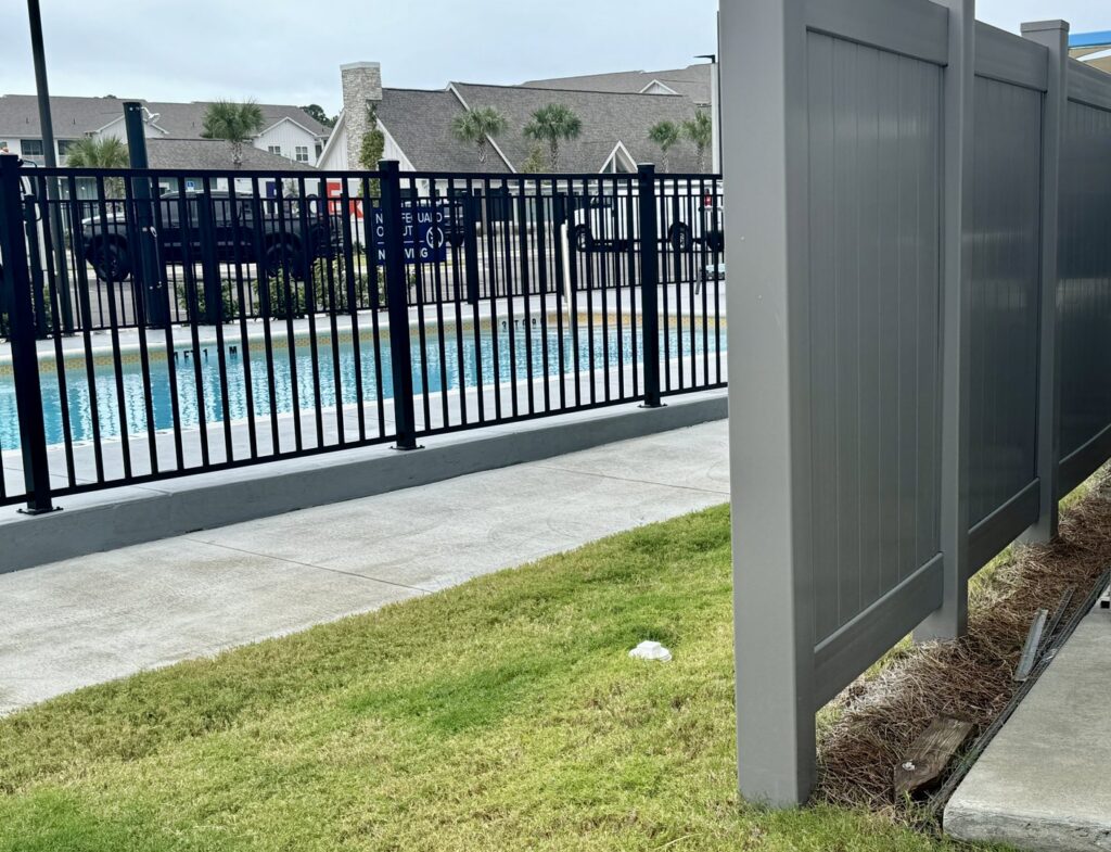 A black ornamental pool fence and a gray privacy fence installed by Superior Fence & Rail of North Shore in Gulfport, MS.