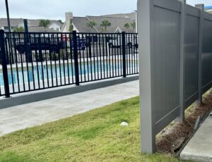 A black ornamental pool fence and a gray privacy fence installed by Superior Fence & Rail of North Shore in Gulfport, MS.