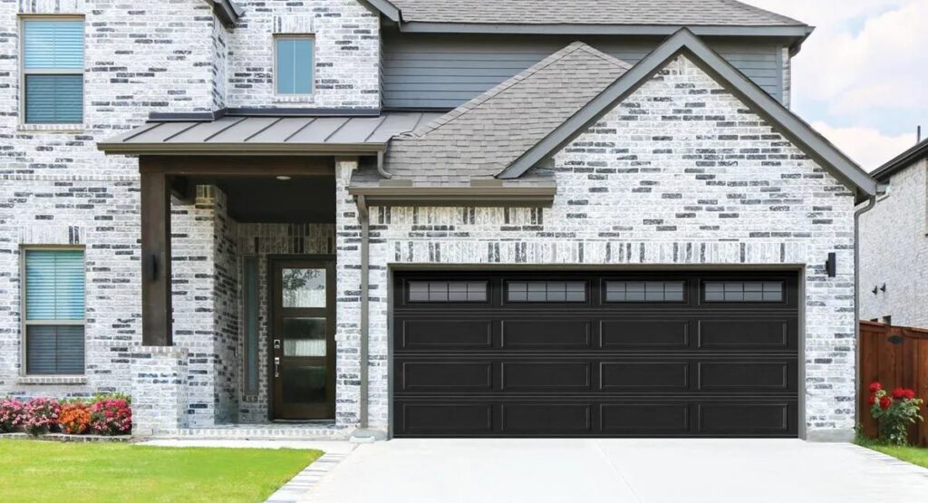 A black panel garage door with top windows installed on a modern residential house by Overhead Doors Unlimited, LLC in Appleton, WI.