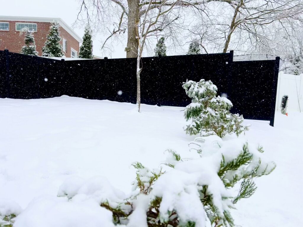 A black privacy fence installed in a snowy backyard, a project by Sol Fence LLC in Evansville, IN.