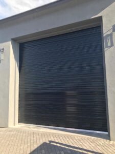 A newly installed black roll-up garage door on a commercial or modern residential building by Sonoran Garage Doors in Mesa, AZ