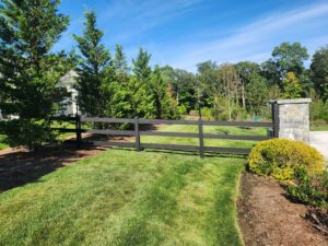 A black three-rail fence with a decorative stone pillar entrance, installed by H&M Fence, LLC in Norwalk, CT.