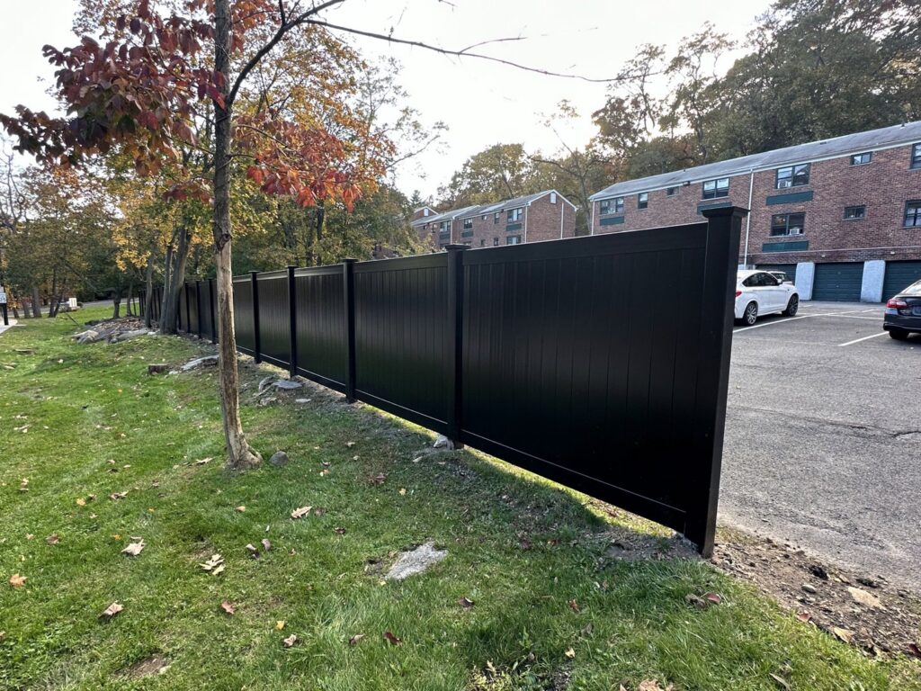 A black vinyl privacy fence installed along a parking lot by Quality Fence Inc. in Peekskill, NY.