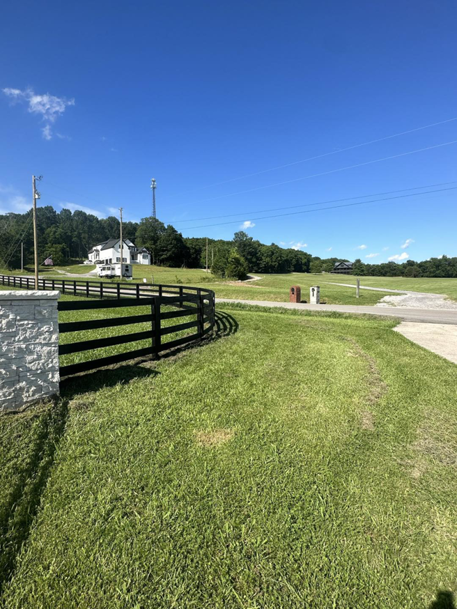 A black wooden fence with a stone pillar entrance leading to a property, installed by Pileggi Fence Painting in Franklin, TN