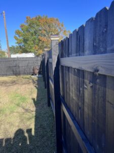 View of the posts and rails of a black wooden privacy fence installed by Dallas' Custom Carpentry in Alexandria, LA.