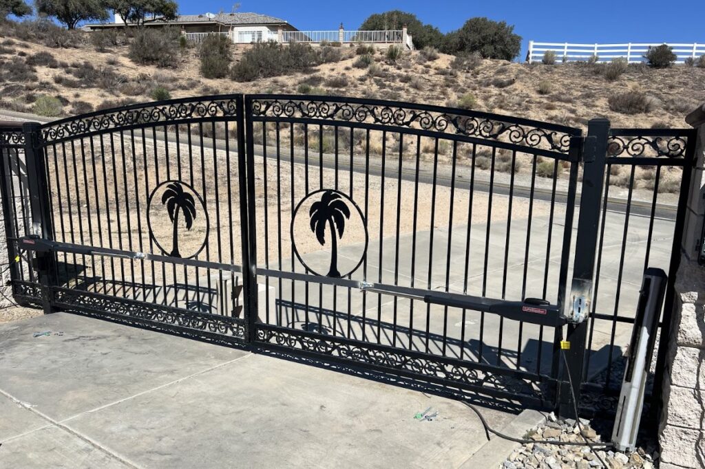 A large black wrought iron automatic double gate featuring decorative palm tree cutouts, installed by True American Fence Supply and Construction in Anaheim, CA.