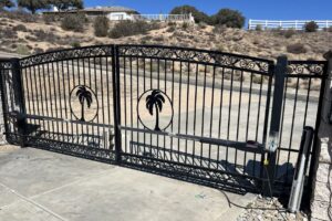 A large black wrought iron automatic double gate featuring decorative palm tree cutouts, installed by True American Fence Supply and Construction in Anaheim, CA.