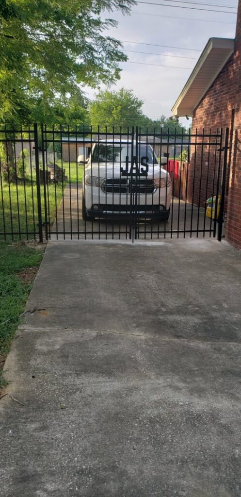 A black wrought iron double gate installed across a residential driveway by Pride Fence LLC in Overland Park, KS.