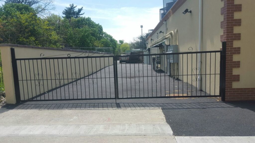 A newly installed black wrought iron driveway gate by Excel Gates & Services Inc. in New Haven, CT